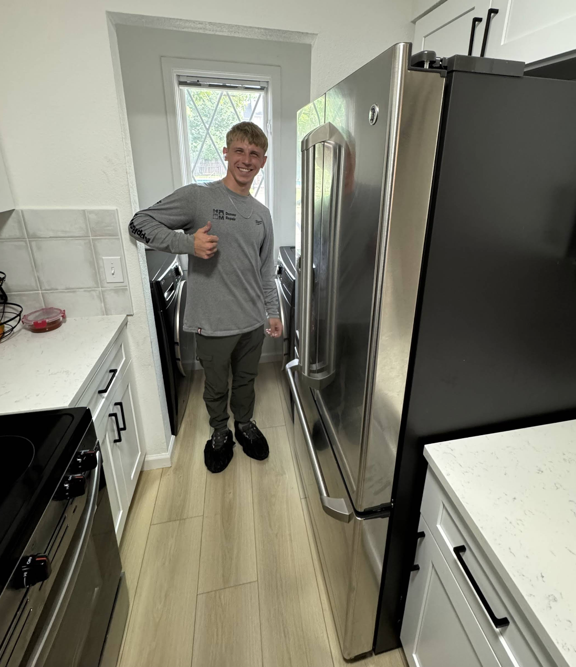 Gena in front of a large refrigerator after a successful repair — Denver metro