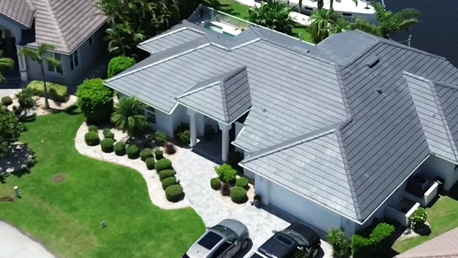 Drone view of a gray tile roof by Shea Roofing on a canal-front home