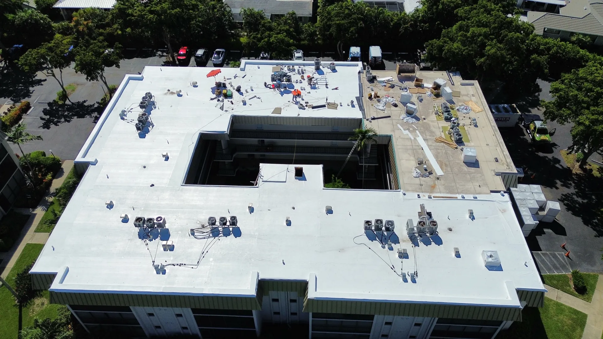 Aerial view of a condominium wing with a new white TPO roof and rooftop units