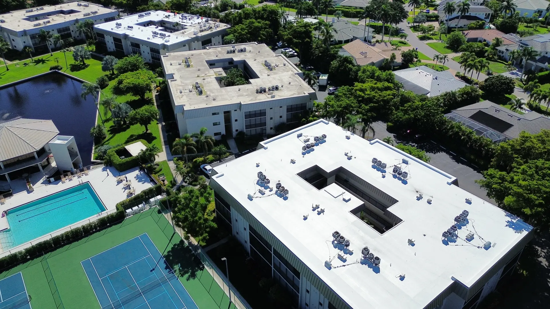 White TPO roof on a condominium building near the pool and tennis courts