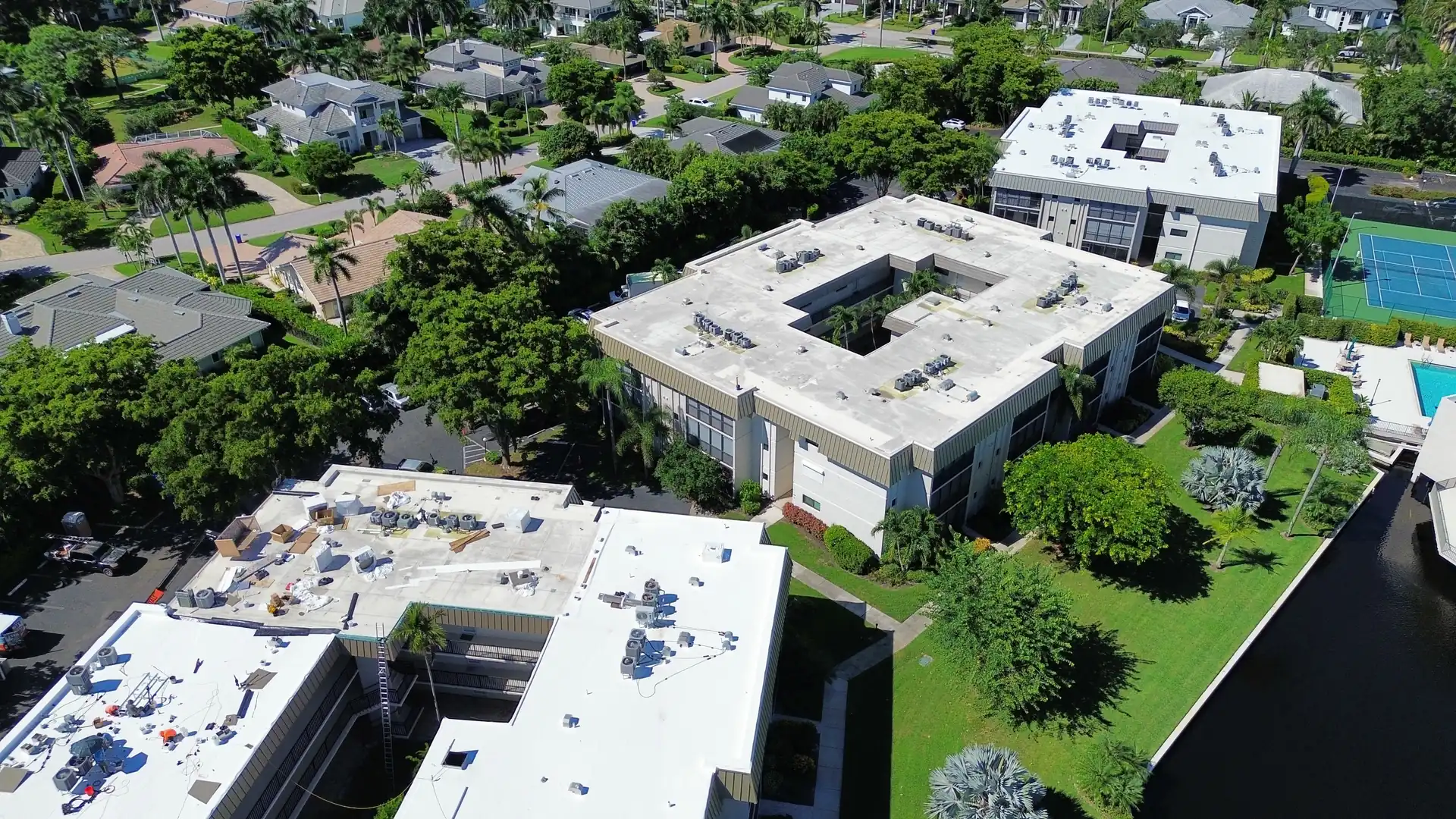 Condominium community with several low-slope buildings, white TPO roofs in front