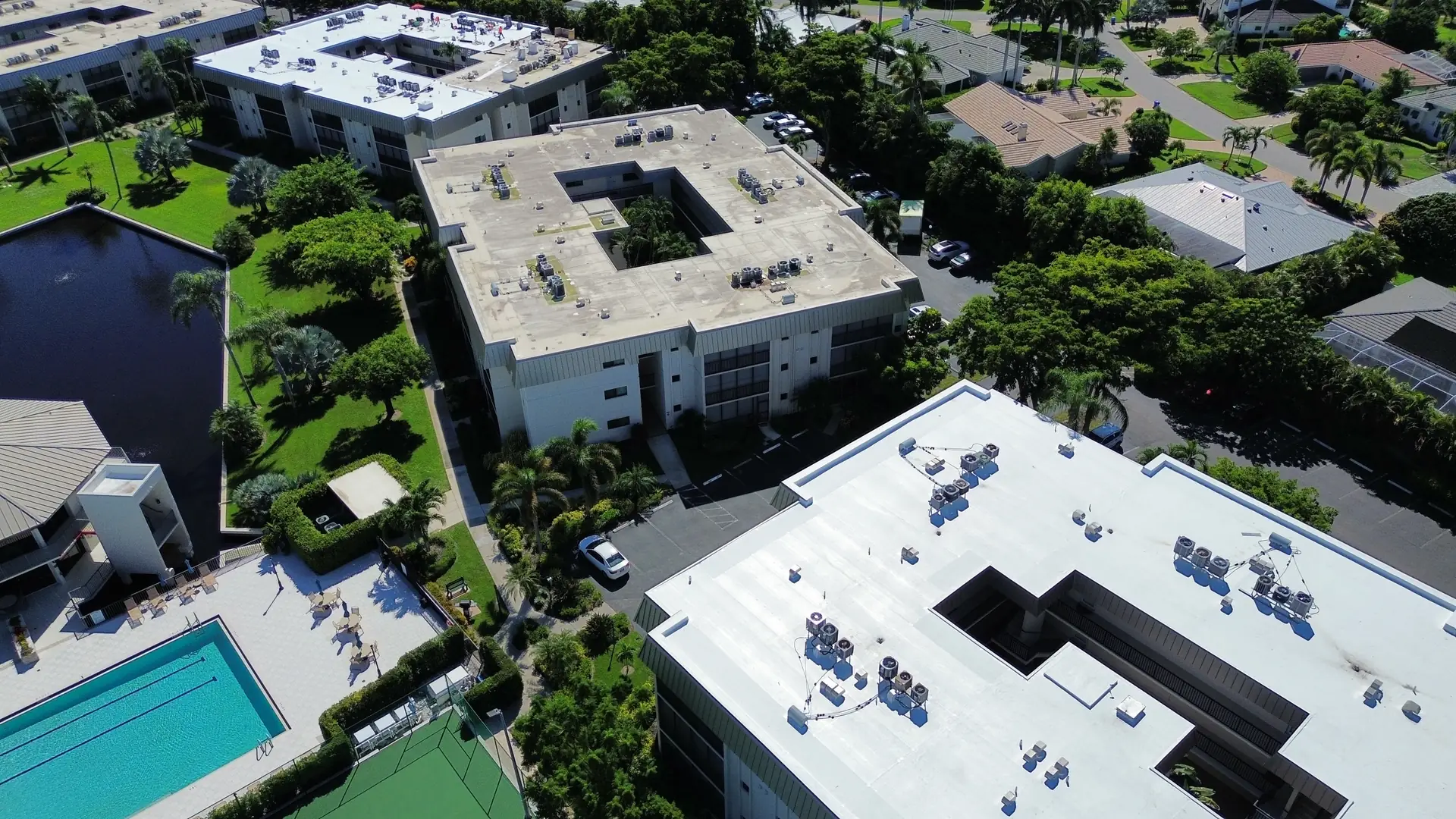 Condominium buildings with white TPO roofs beside the community pool