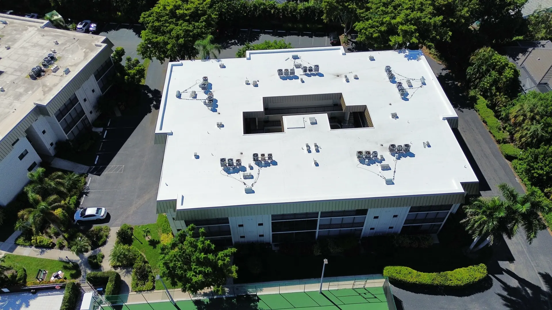 Finished white TPO roof on a condominium building, straight-on drone view