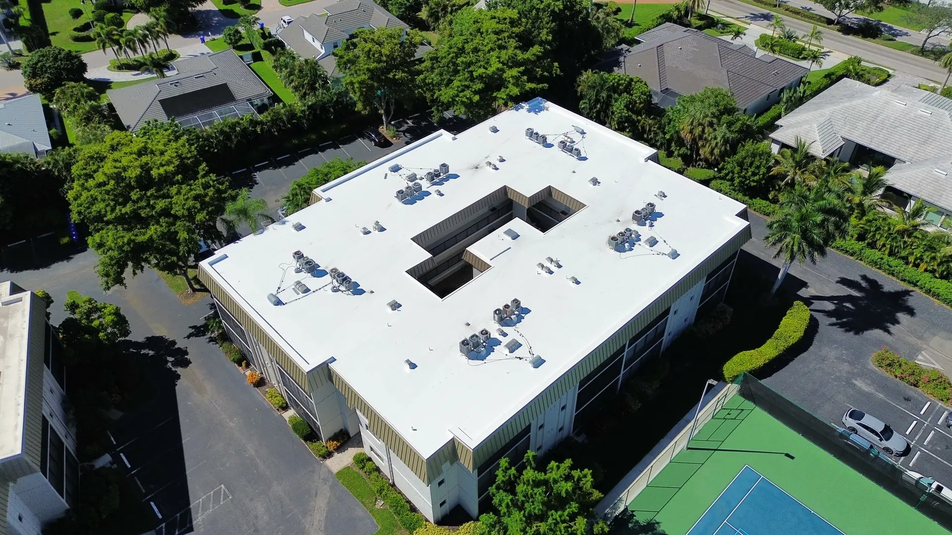 Finished condominium building with a bright white TPO roof, oblique aerial