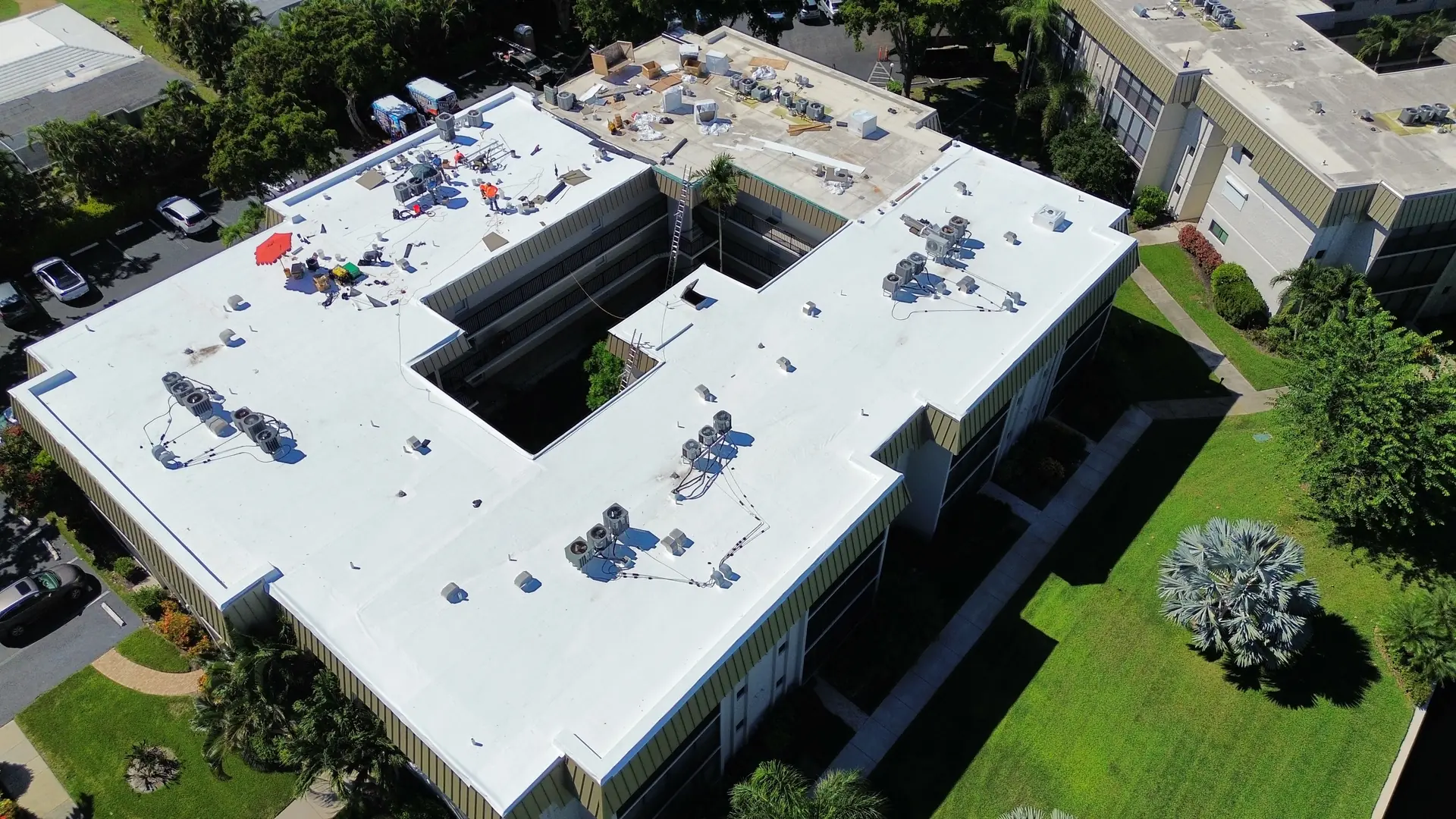 Oblique aerial of a condominium building with a new white TPO roof above the lawn
