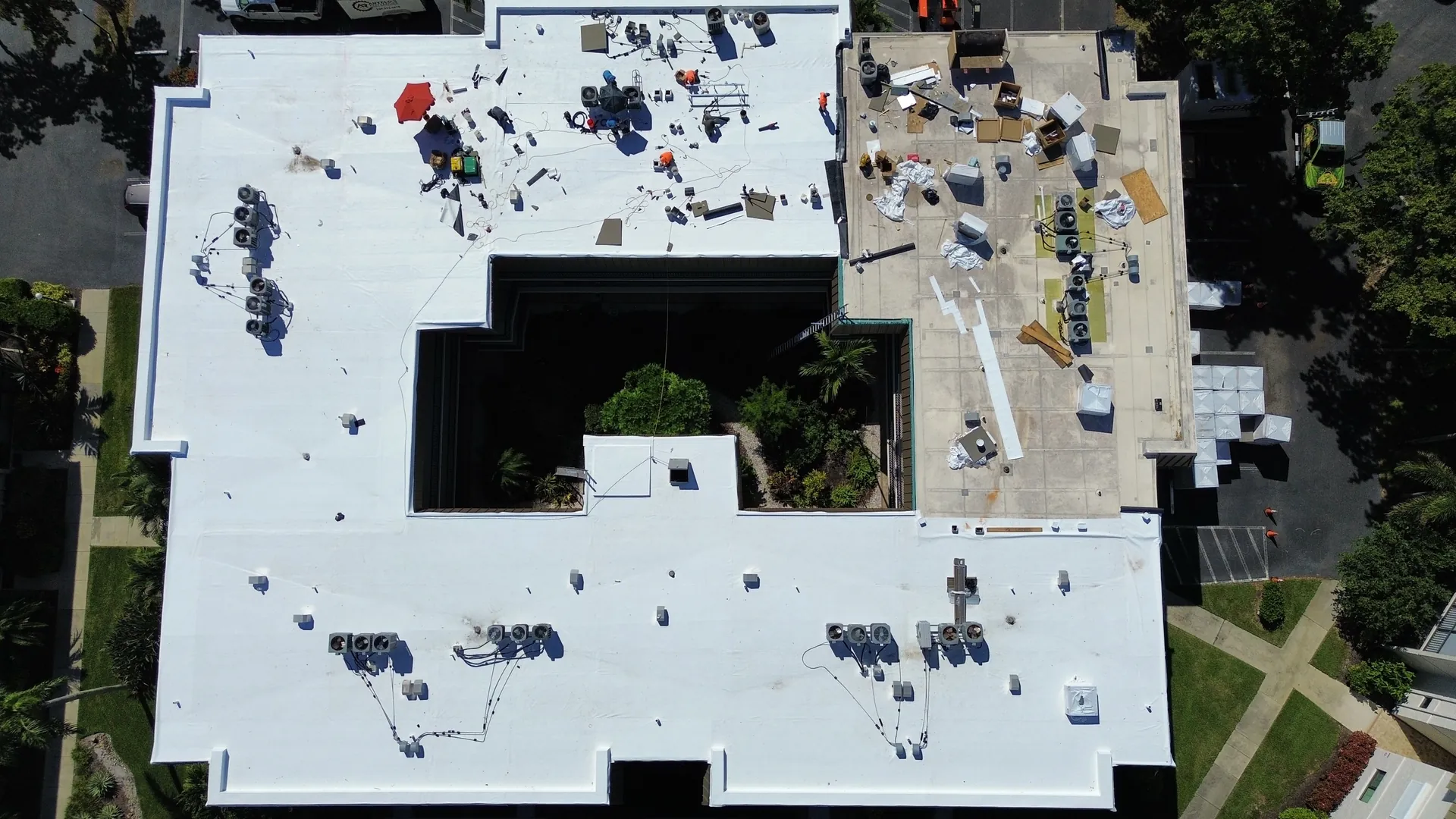 Overhead drone view of a finished white TPO roof around a condominium courtyard