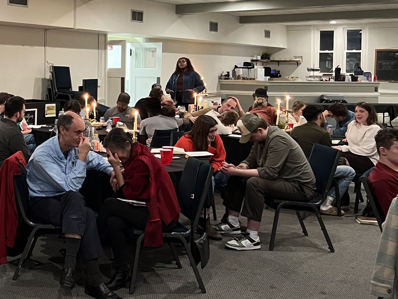 Couples talking and praying together at candlelit tables during a CO session