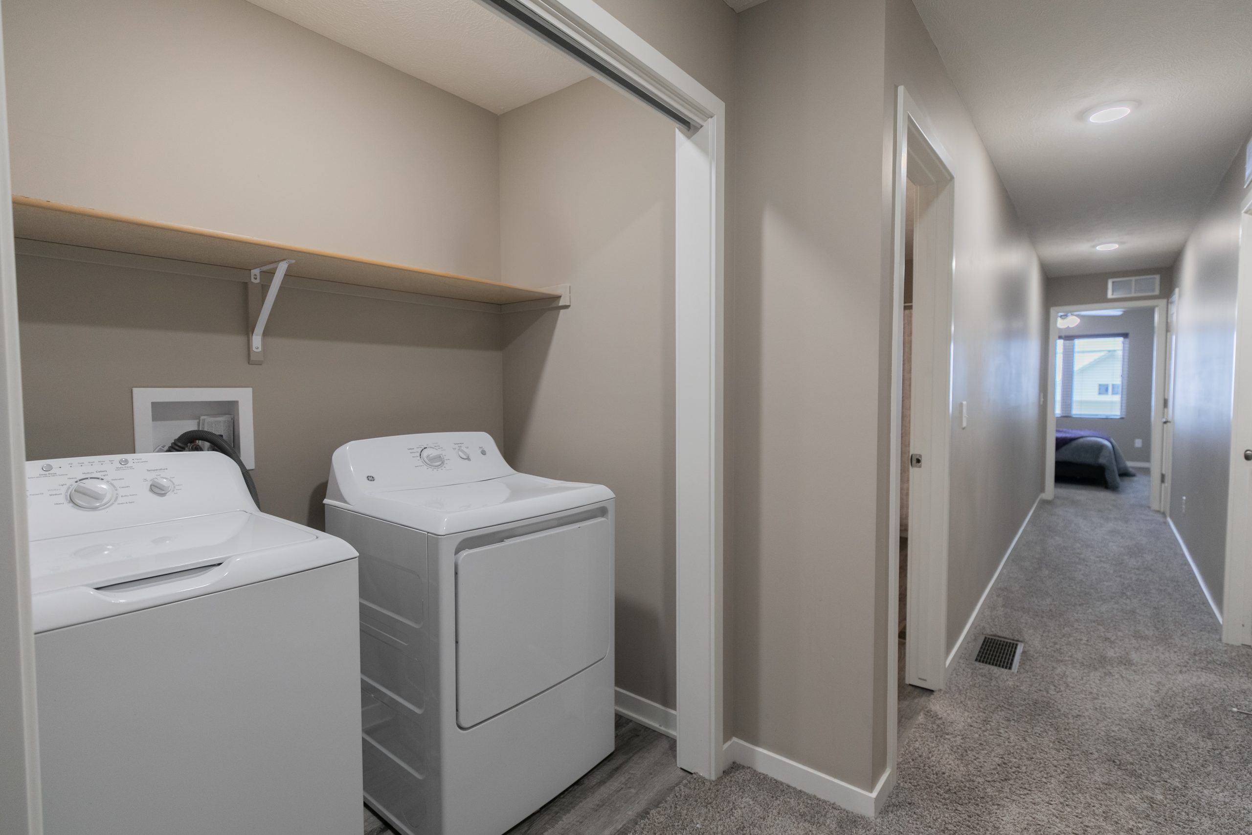 In-unit washer and dryer with hallway leading to bedrooms