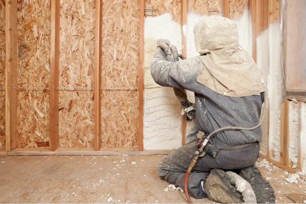 Installer applying open-cell spray foam to wall cavities for 903 Spray Foam in Sulphur Springs, TX
