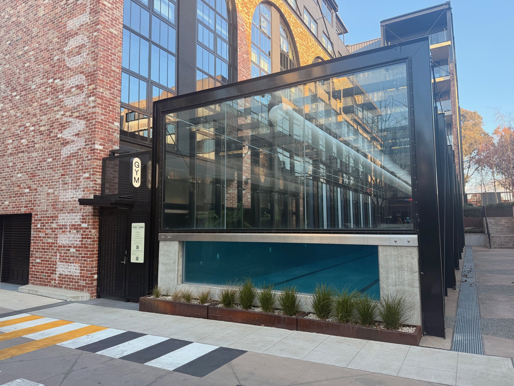 The Kingston Gym + Swim entrance: a black gate beside the glass-walled pool, under the GYM sign