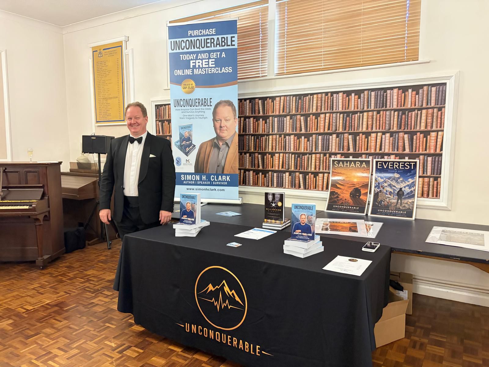 Simon Clark in black tuxedo next to table with his books Simon Clark in black tuxedo next to table with his books
