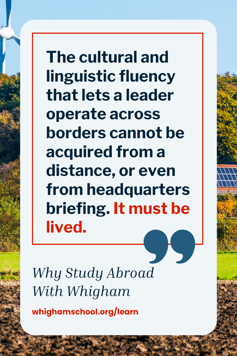 Promotional graphic for The Whigham School featuring a quote about cultural and linguistic fluency being developed through lived international experience rather than classroom instruction alone. The design includes a landscape with wind turbines and solar panels in the background, large quotation marks, the phrase “Why Study Abroad With Whigham,” and the website whighamschool.org/learn.