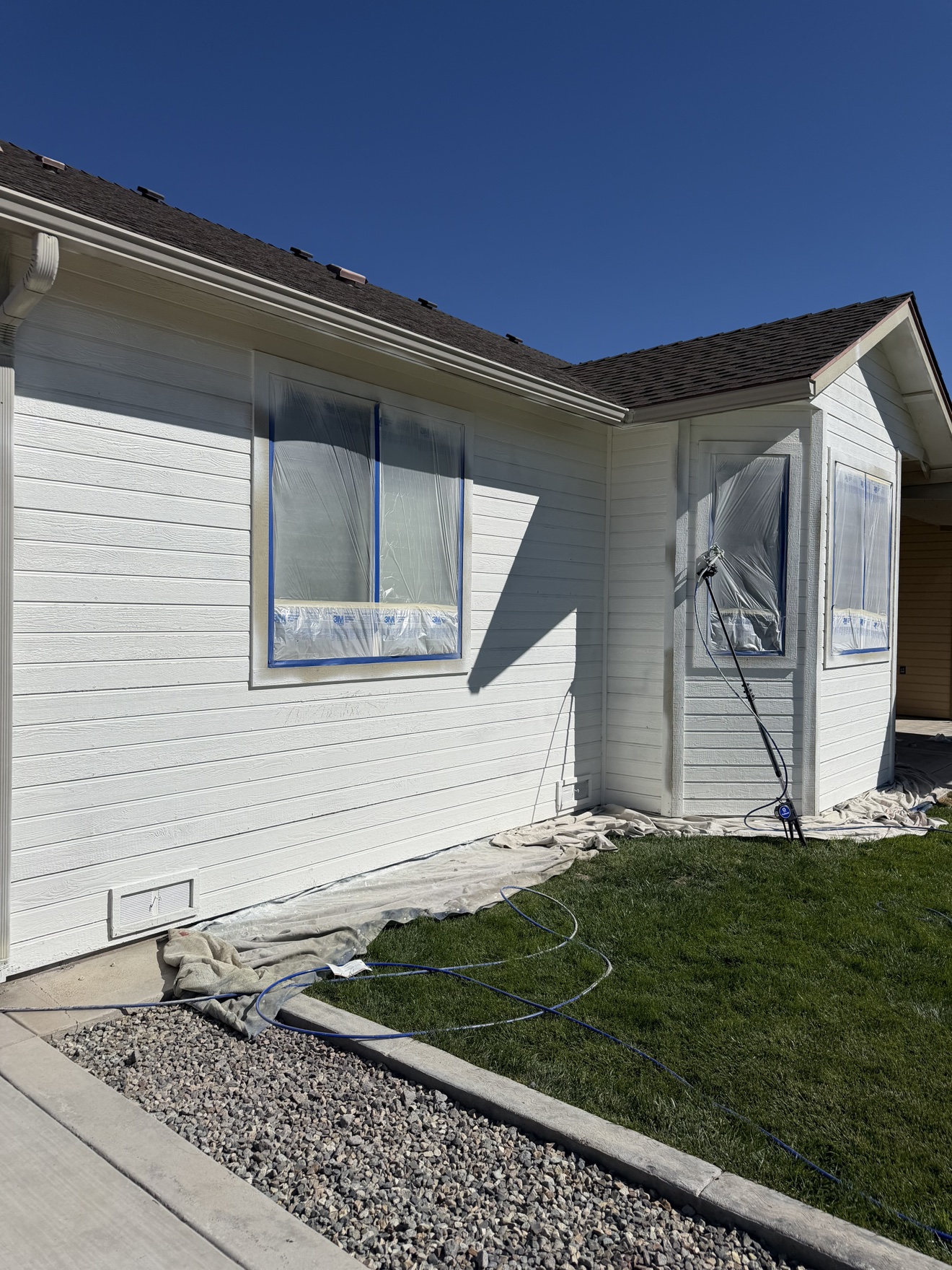 During: spray work in progress — tan siding going to crisp white