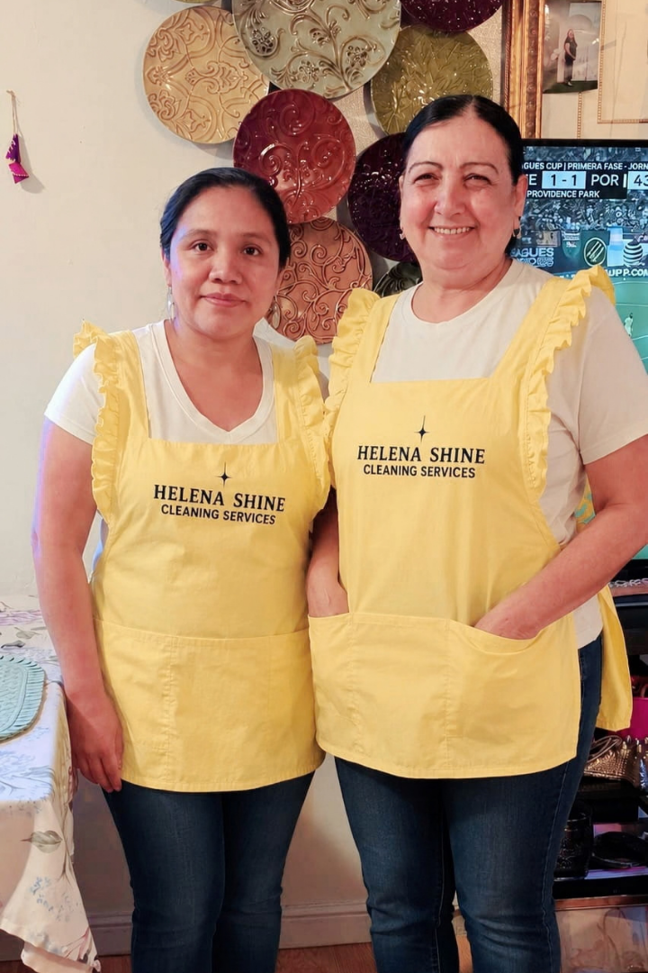 Two Helena Shine cleaning team members in yellow aprons working together in a bright home