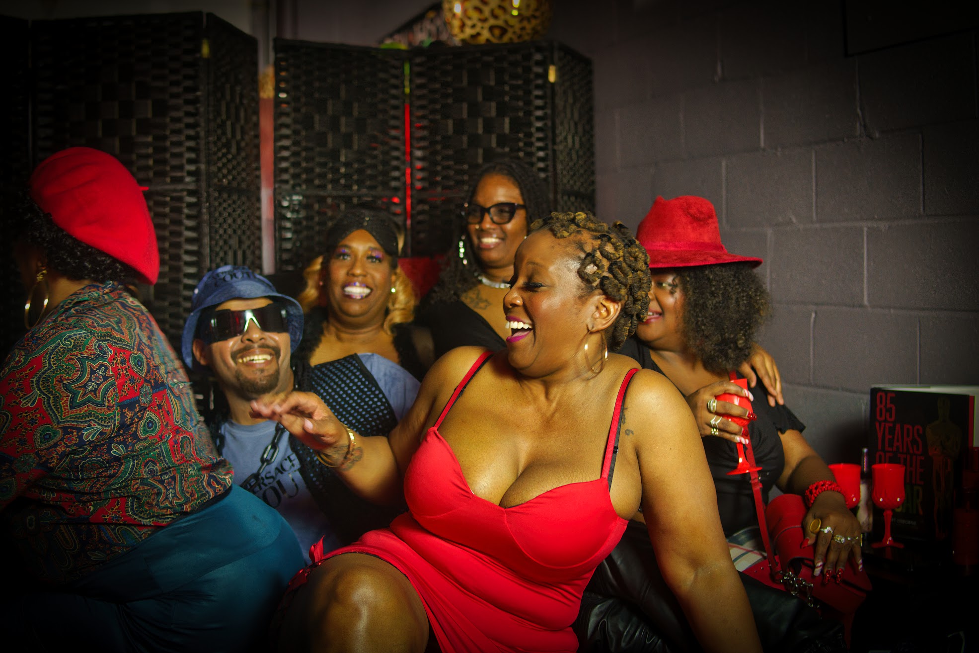 Group portrait on the theatrical Alter Ego bed set with dramatic red and purple lighting