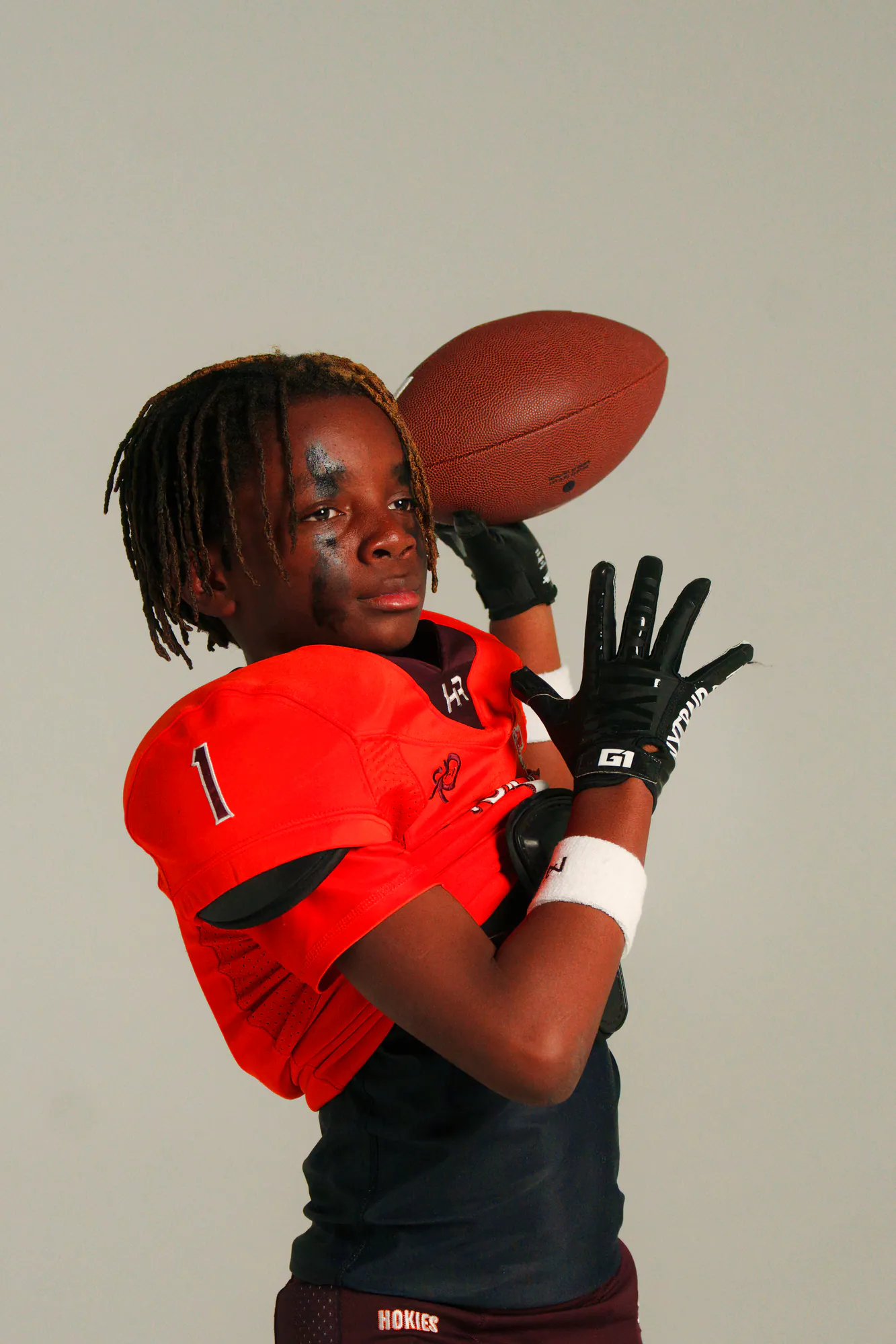 Football athlete in red uniform with ball over shoulder at 757 Dream Lab Studio