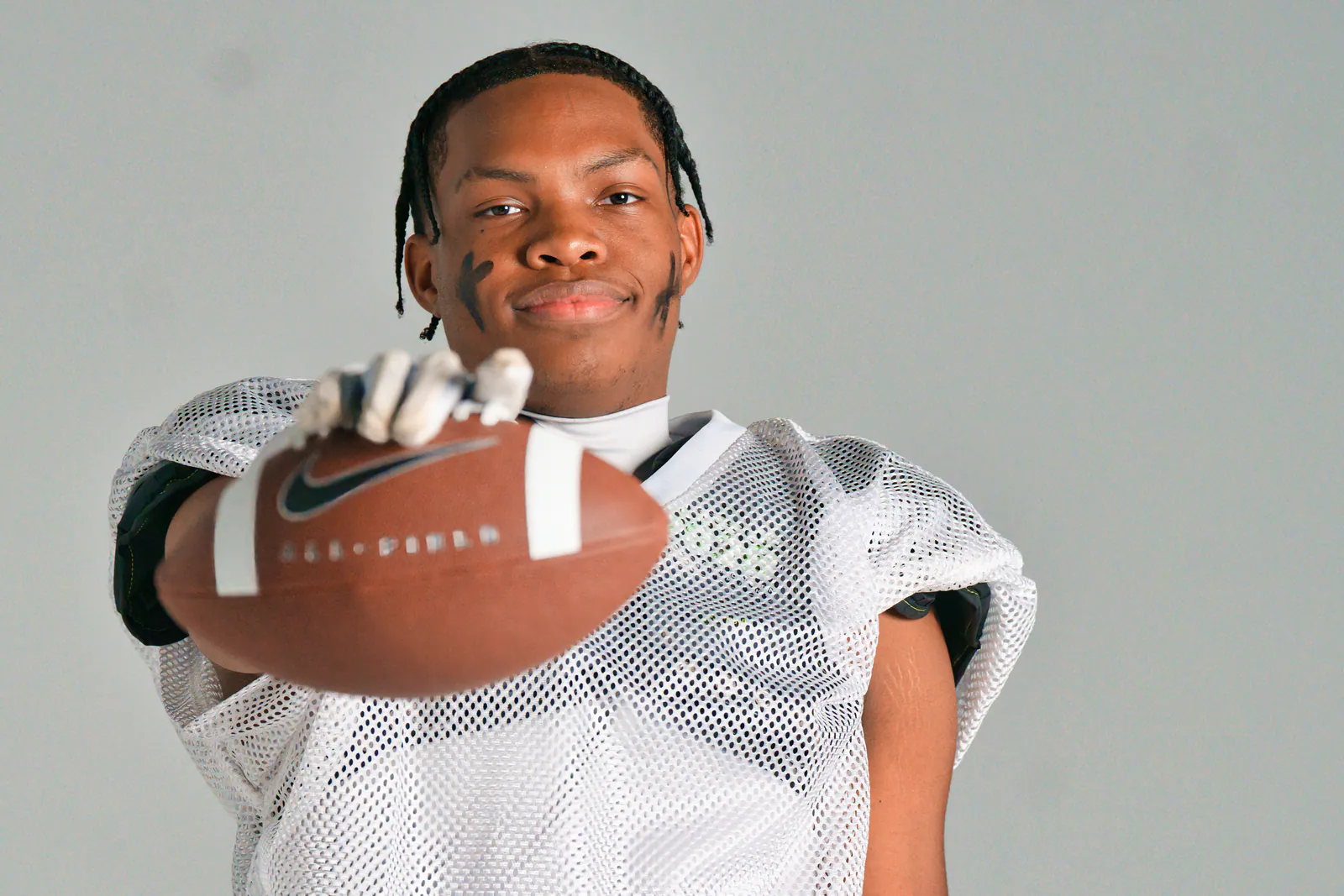 Football athlete extending ball toward camera at 757 Dream Lab Studio