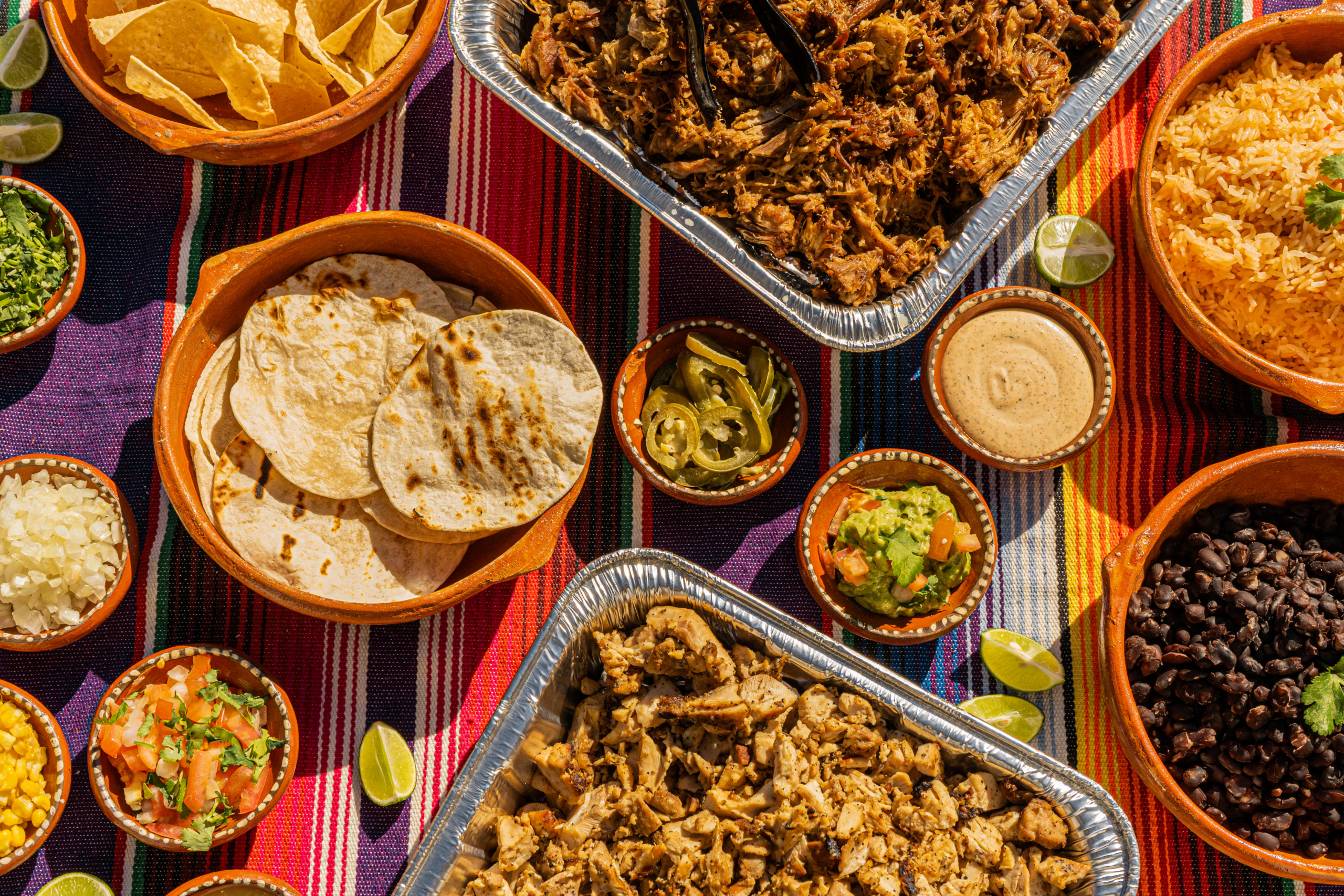 Bright, appetizing Mexican tacos served in colorful Talavera ceramic dishes with lime wedges, cilantro, onions and salsa