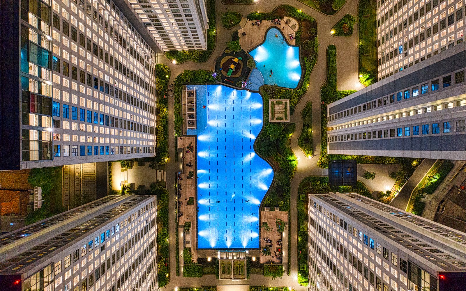 Aerial view of an illuminated multifamily property and pool courtyard