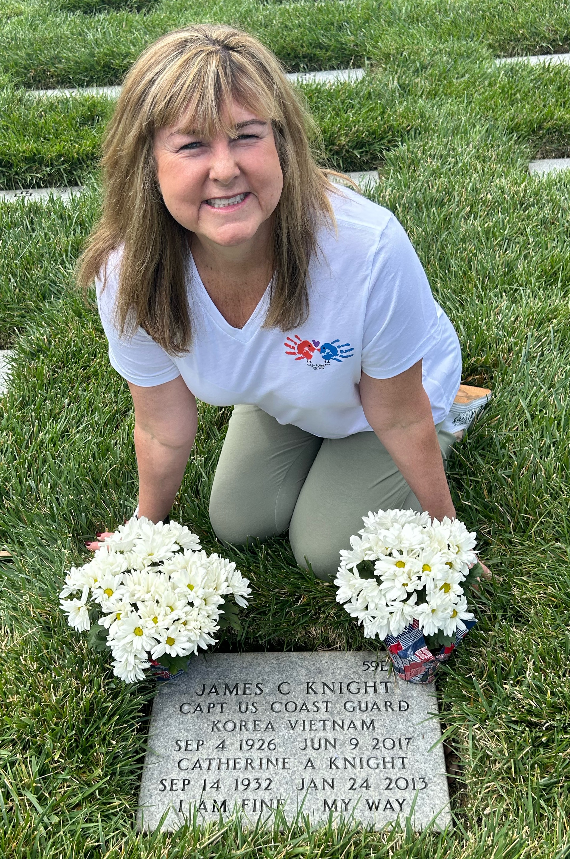 Kim at her parents' grave wearing the Red Bird Blue Bird Foundation shirt