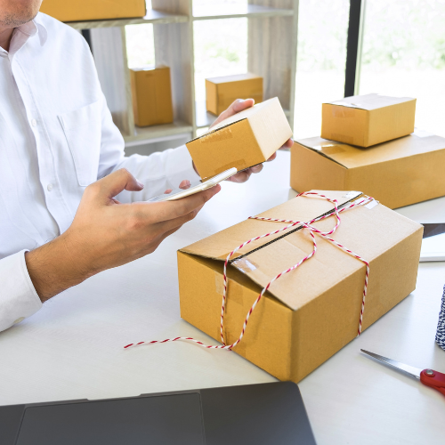 Shop owner calculating cost-to-fulfill while packing online orders]