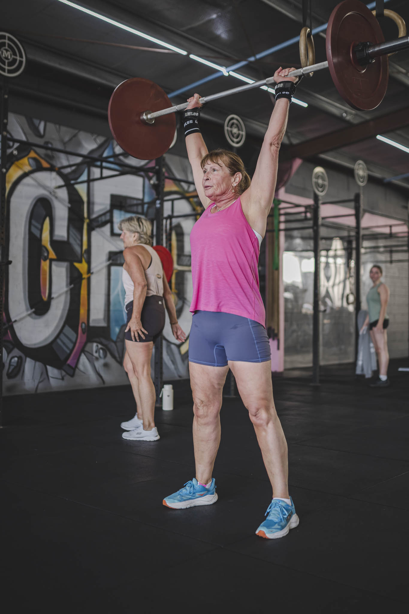 A coach guiding a member through a barbell movement