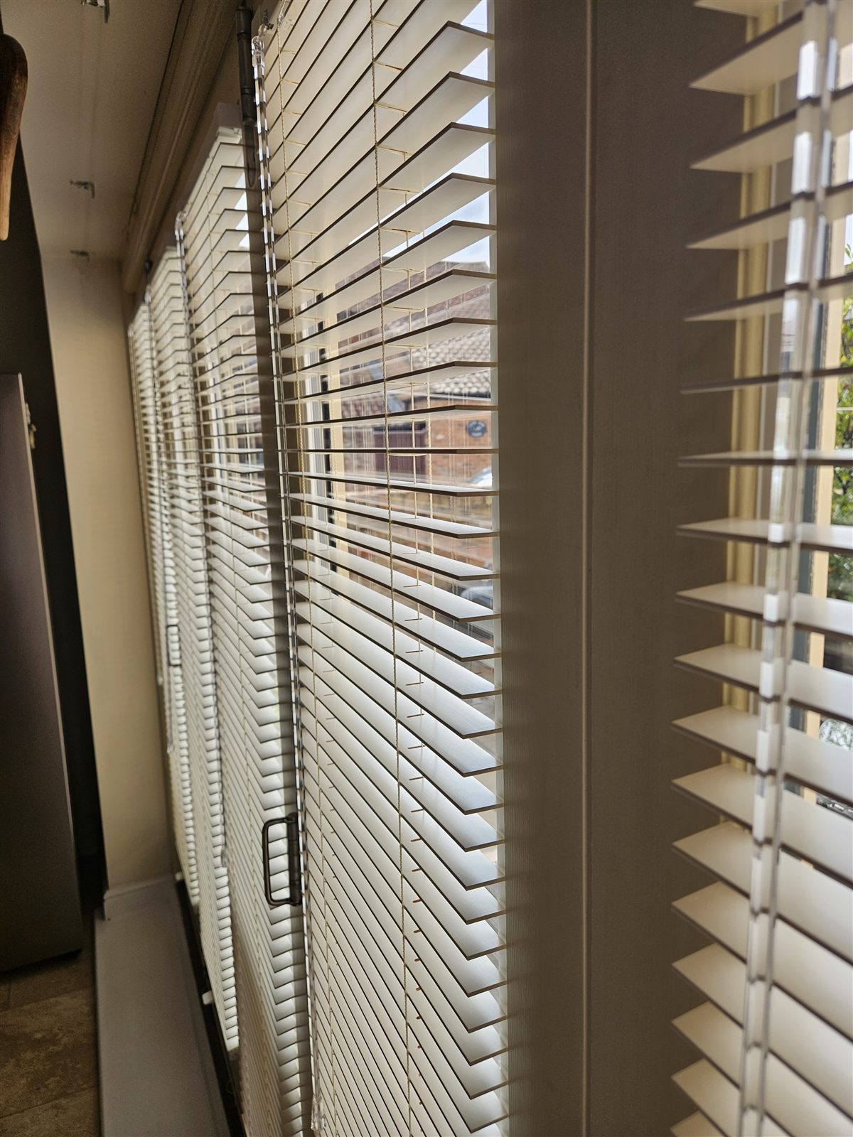Cream wood venetian blind slats tilted for privacy on a bi-fold door, fitted by Eclipse SBC in Retford
