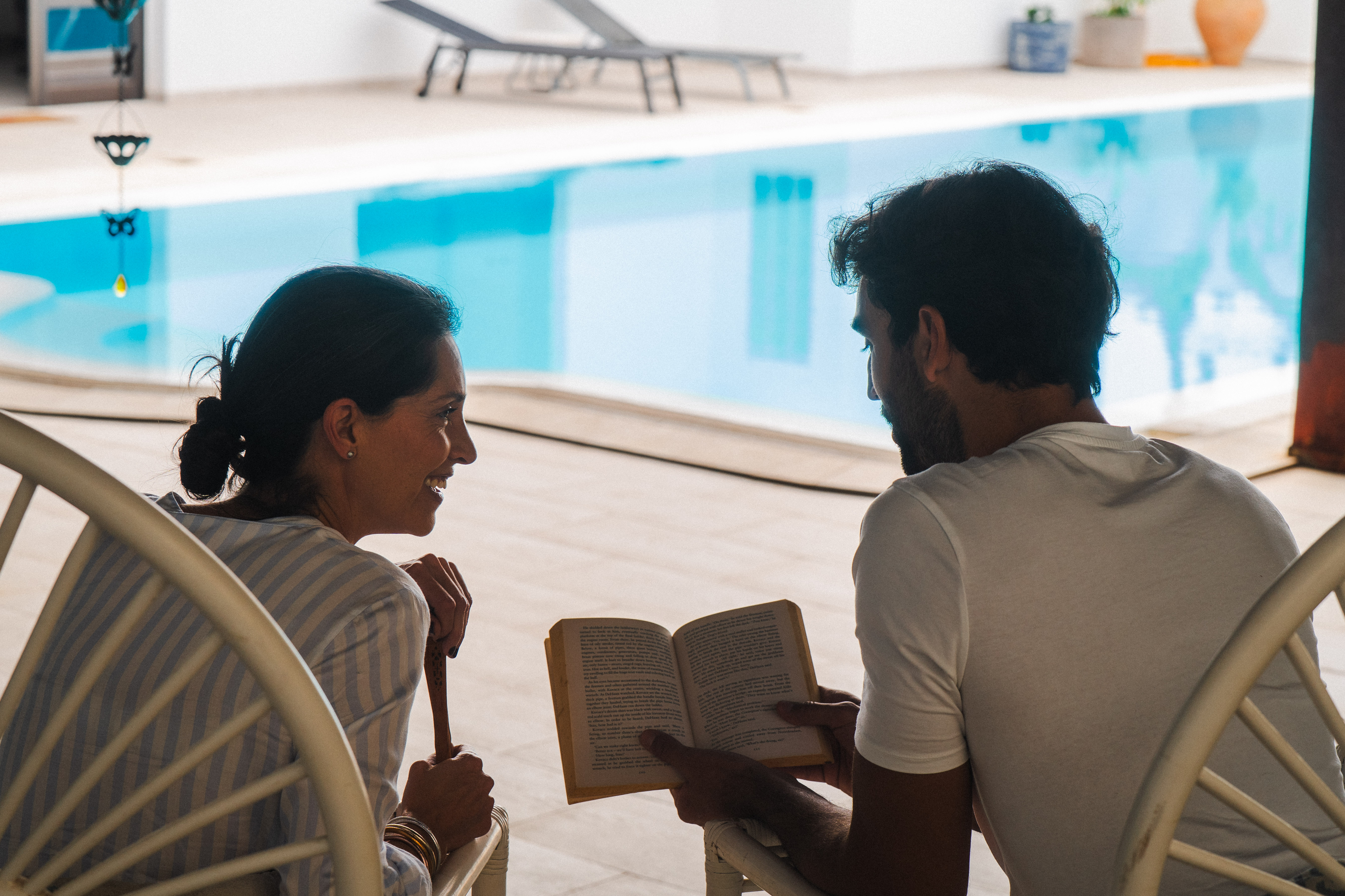Pareja leyendo y relajándose junto a la piscina de su villa