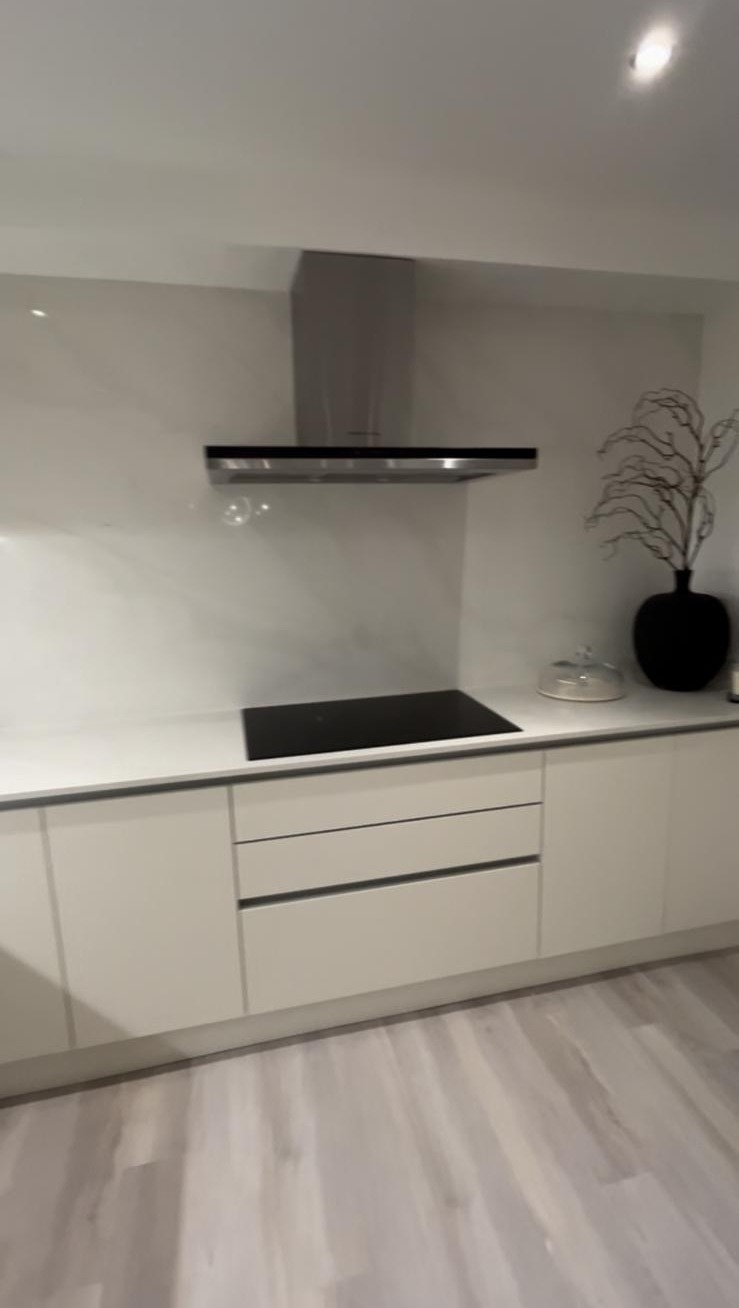 Finished cream handleless kitchen with marble-effect splashback