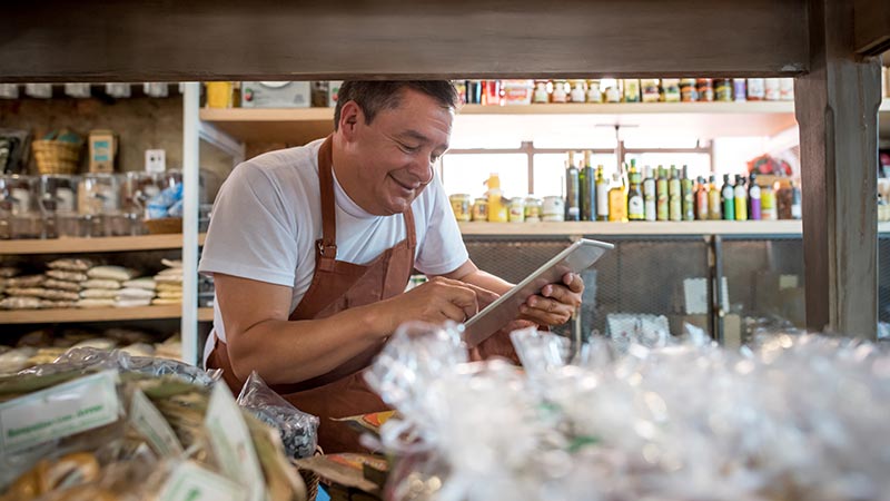 A shop owner reviewing his business on a tablet inside his store