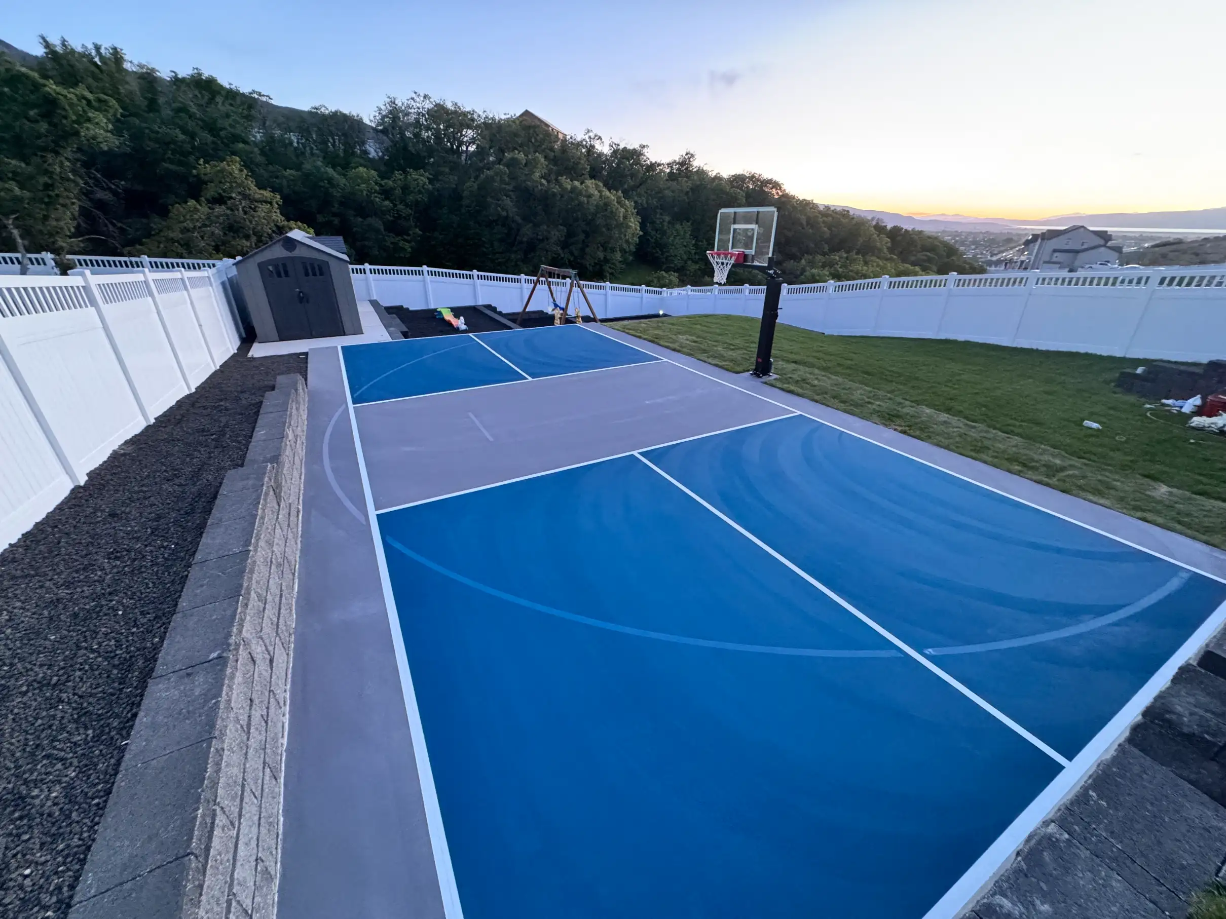 Hillside blue and grey multicourt with basketball hoop at sunset