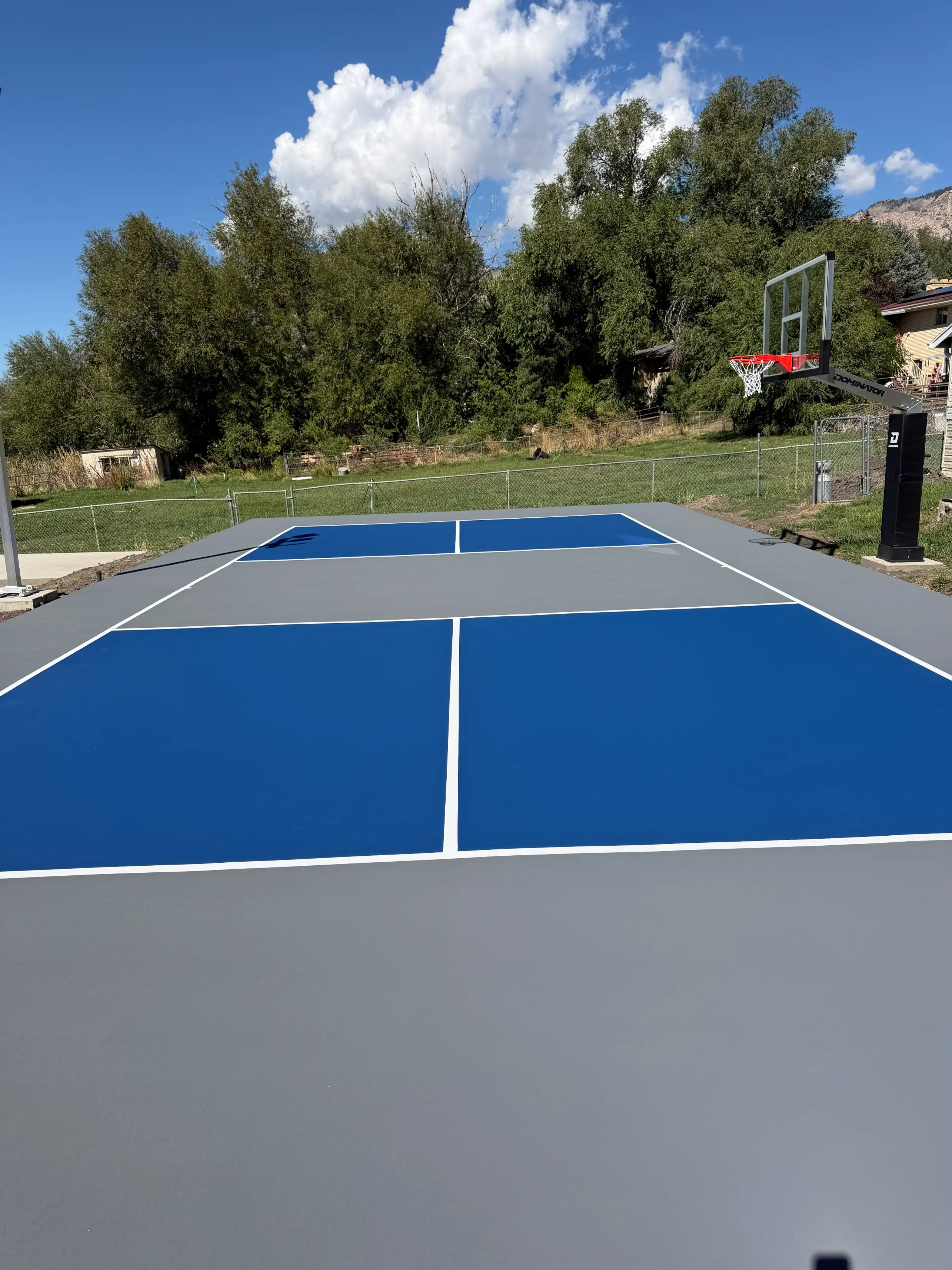 Blue and slate grey pickleball court with in-ground basketball hoop