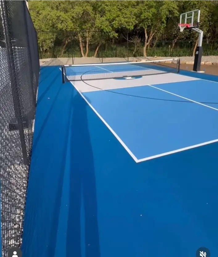 Two-tone blue multicourt with portable pickleball net and basketball hoop