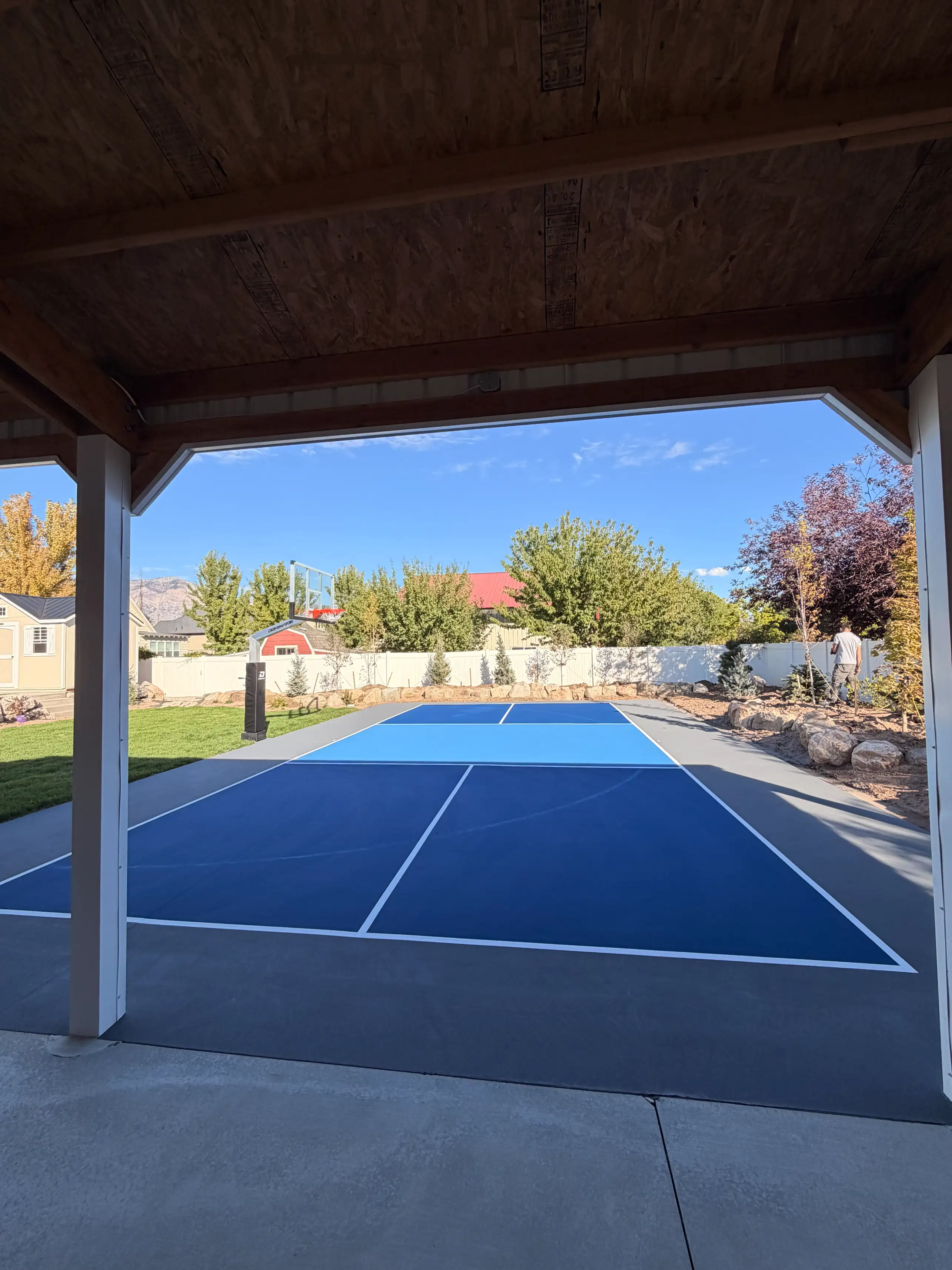 Navy and sky blue pickleball court seen from a covered patio