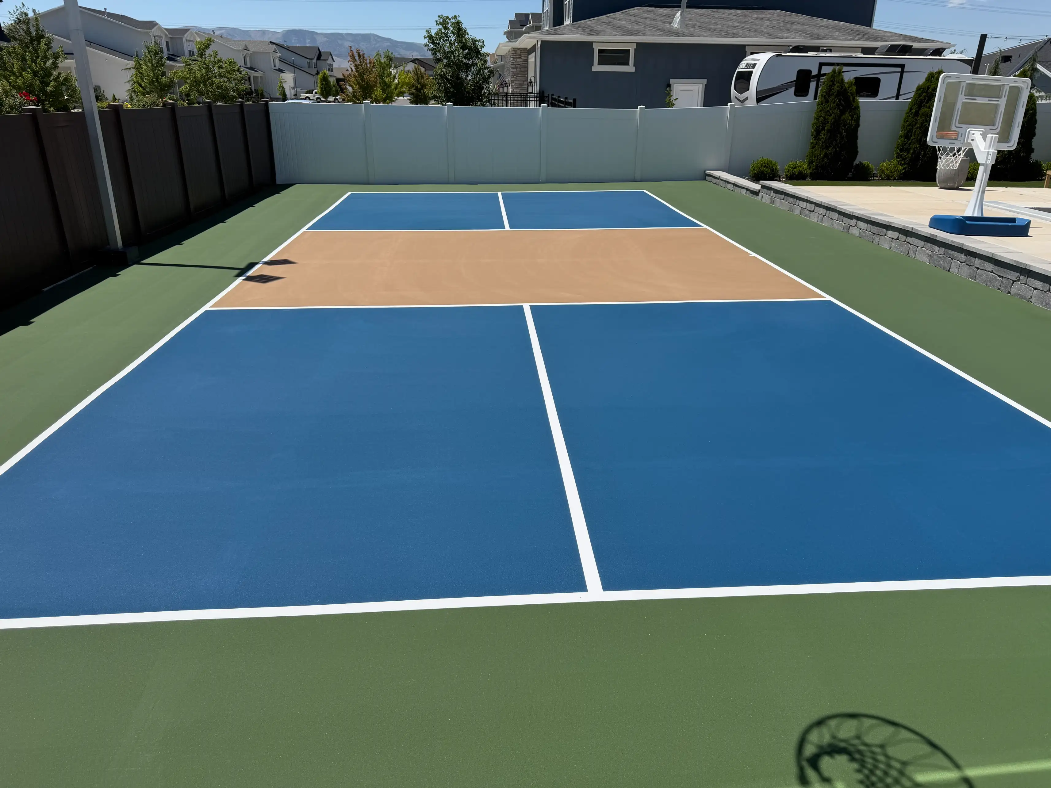 Blue pickleball court with tan kitchen and green border