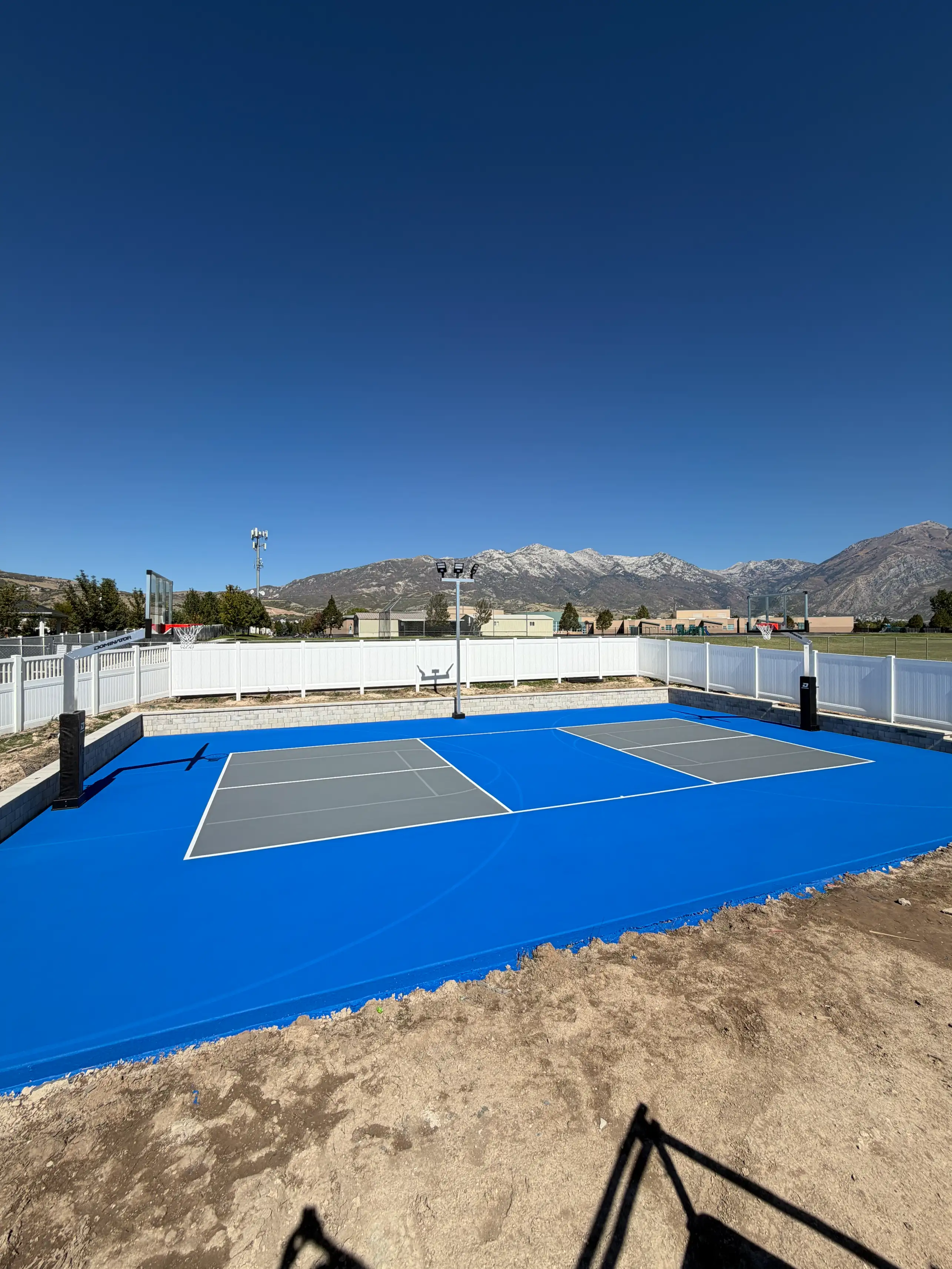 Two grey pickleball courts on a royal blue multicourt base