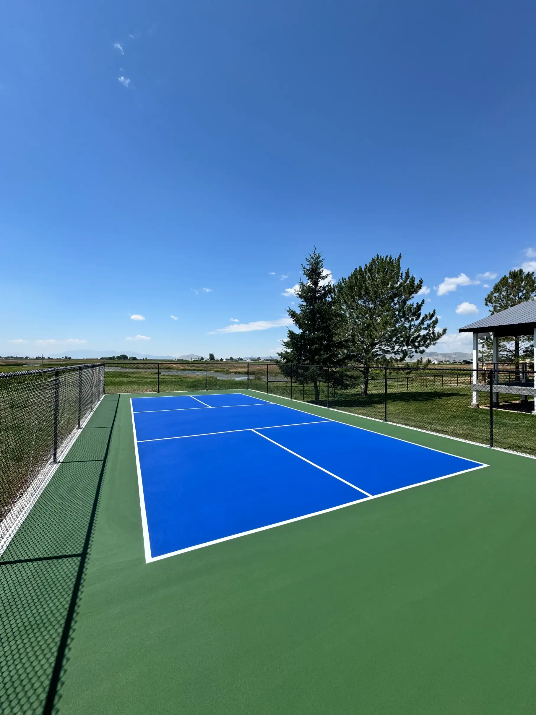 Rural blue and green pickleball court overlooking a pond