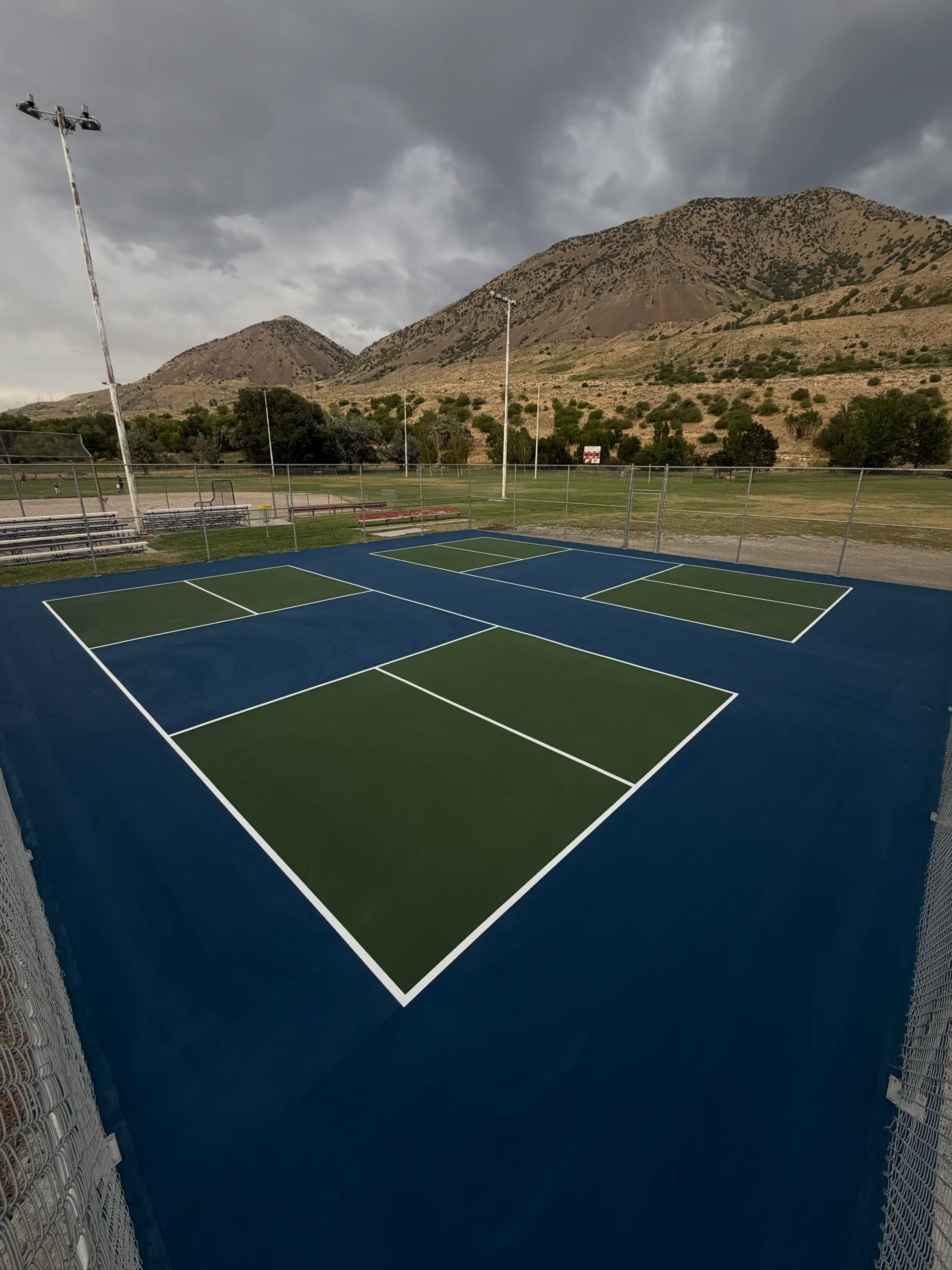 Two navy and green park pickleball courts beneath the foothills