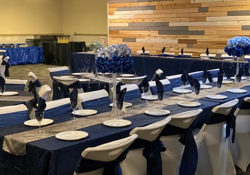 Banquet tables set with navy linens and white chair covers for an event by Main Event