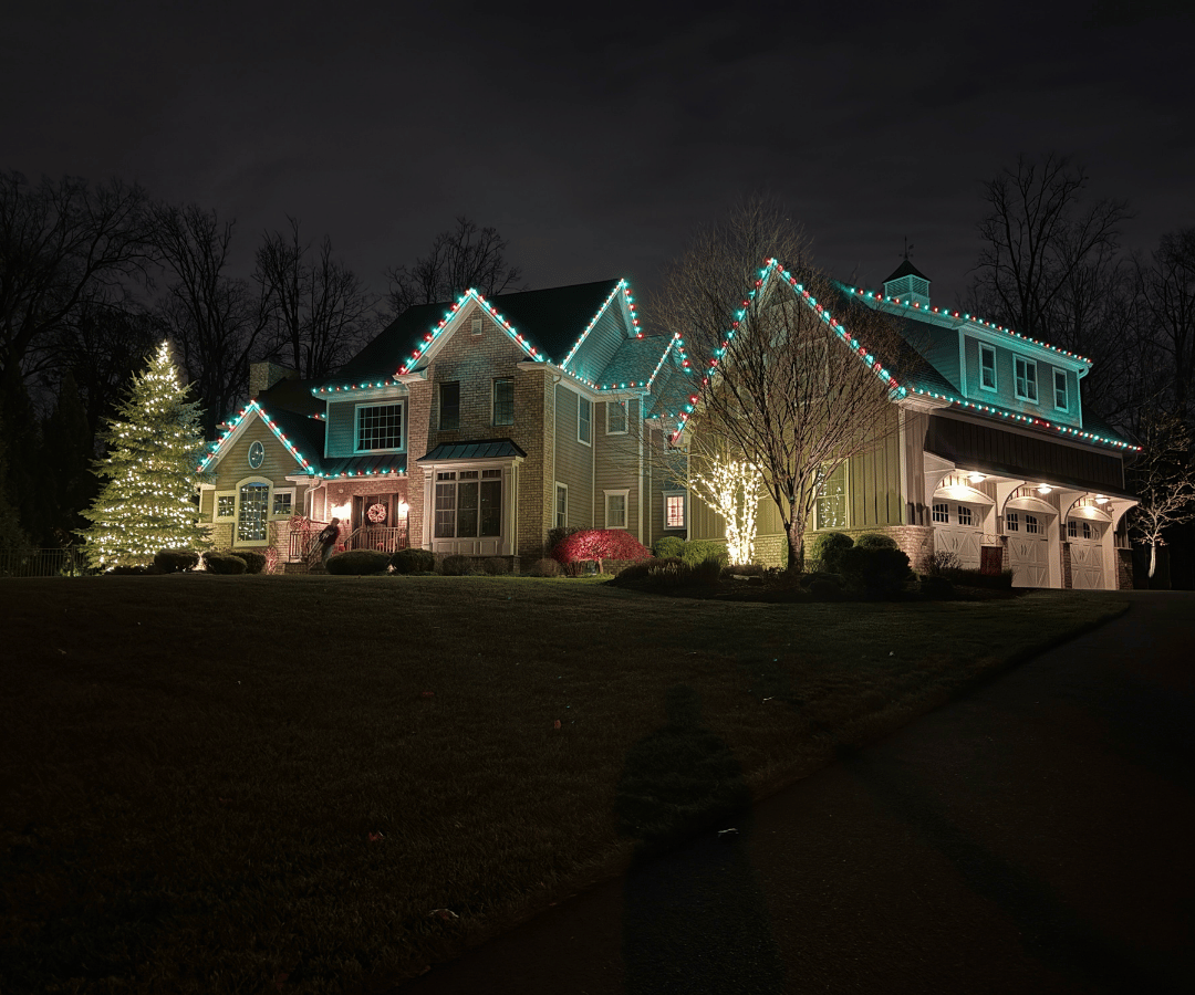 Professional residential Christmas lighting with green accent trees and roofline lights New Jersey