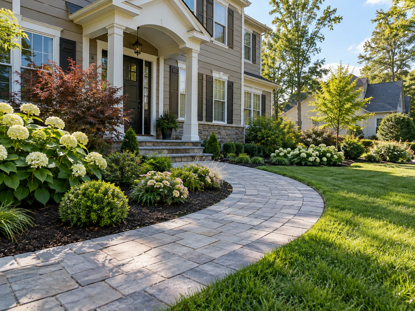 Curved paver walkway running through a planted front lawn