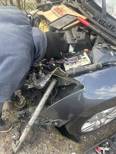 Mechanic working on a severely damaged vehicle’s front end