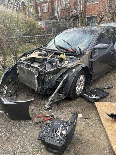 Car undergoing body repair with front bumper and grille removed