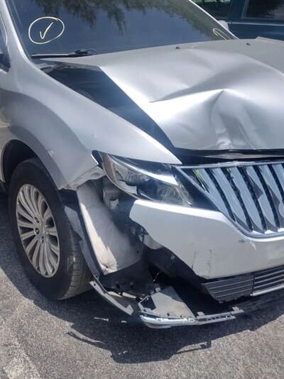 Front-end damage to a silver vehicle after an accident