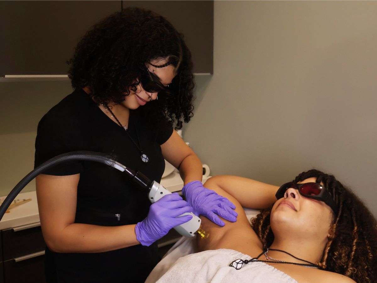 Laser technician treating a client's underarm with the GentleMax Pro, both wearing laser safety glasses, at Ambiance Spa in Houston
