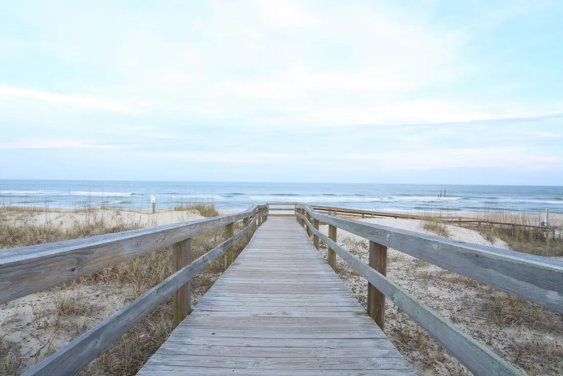 A wooden boardwalk leading over the dunes toward the ocean