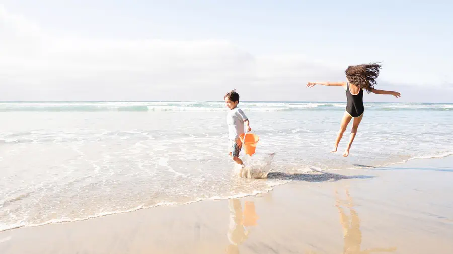 Two children playing in the shallow surf on a calm beach