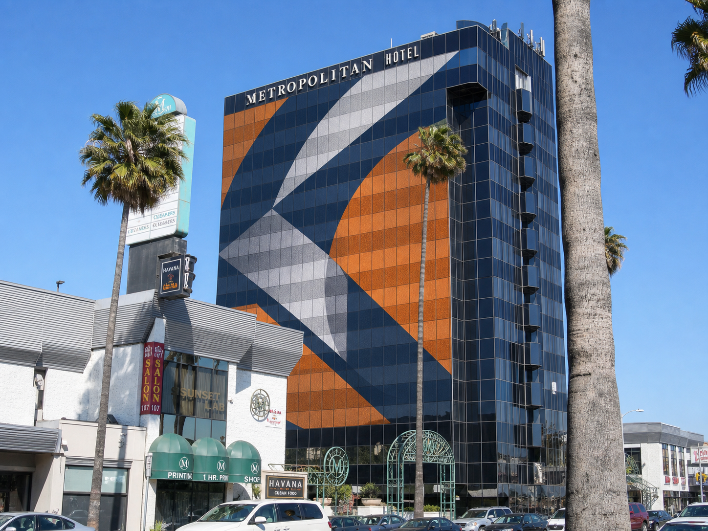 Freeway view of a distant glass building with a visible abstract supergraphic across the facade