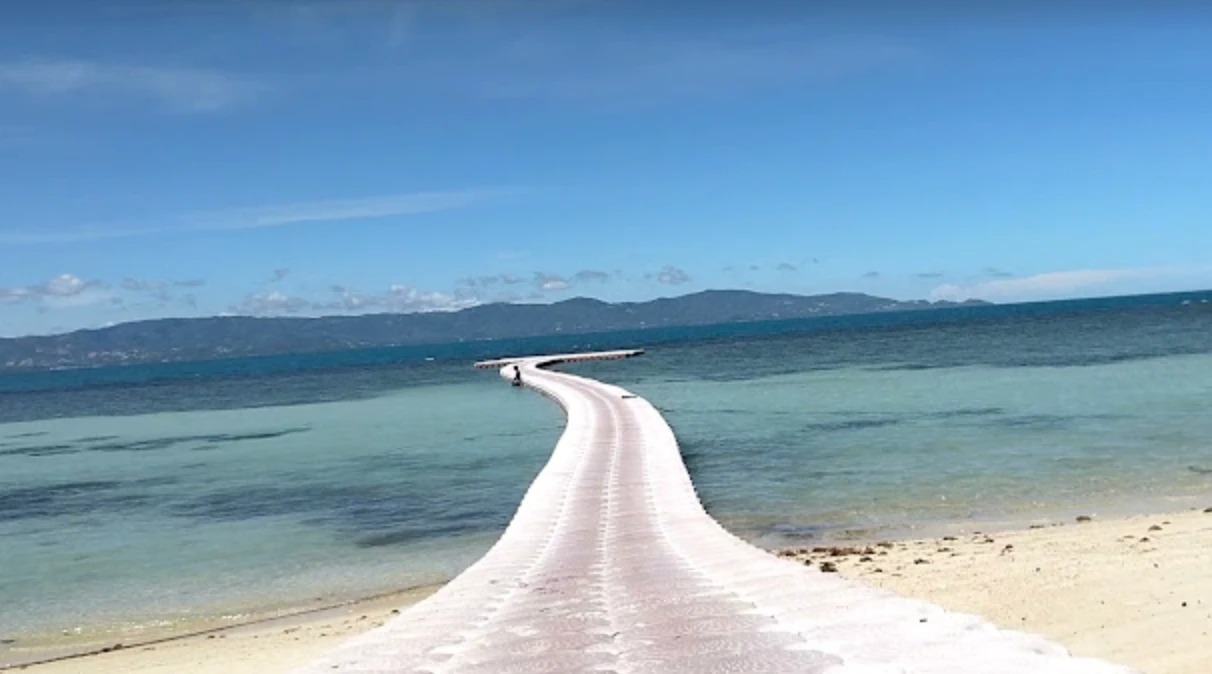 A white floating walkway curving out across turquoise water