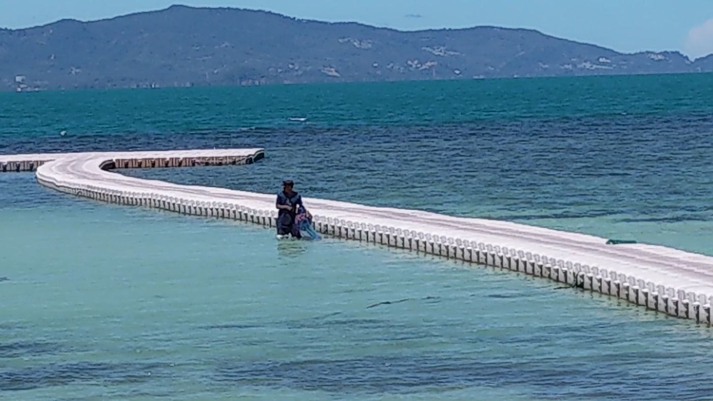 A long floating causeway across the bay toward the mountains